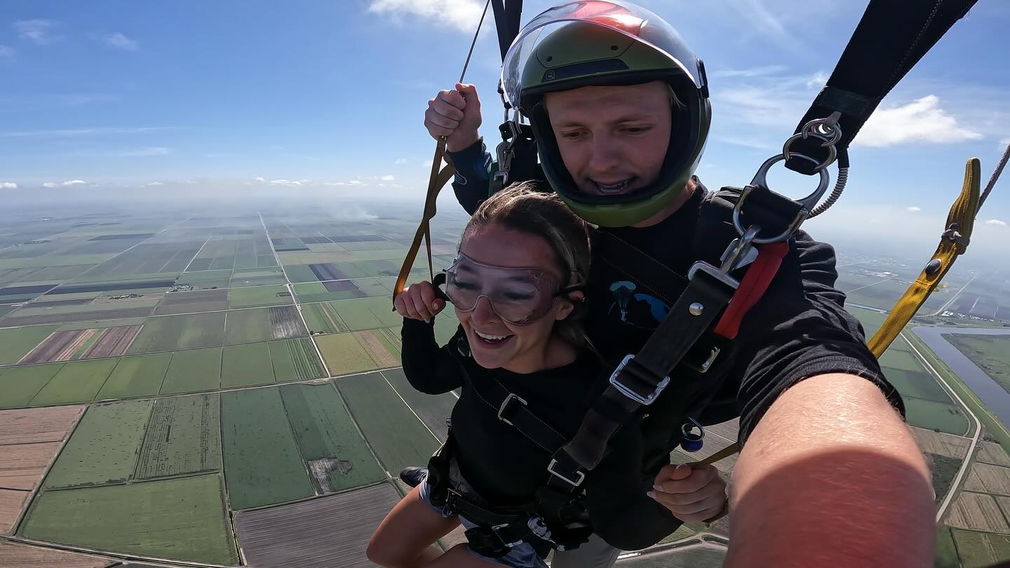 Female tandem skydiver using the toggle to steer a parachute