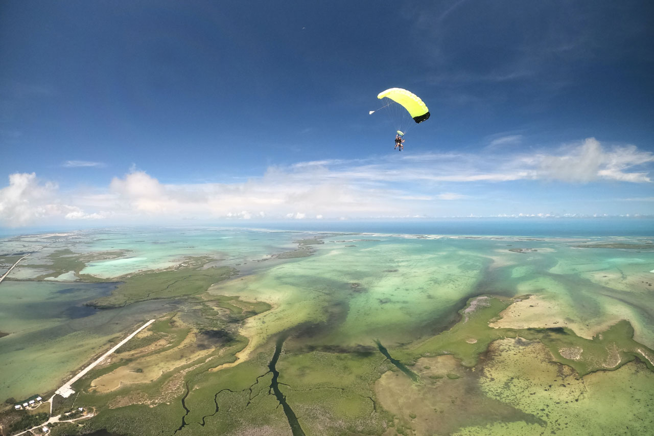 Tandem skydiving pair under canopy above Key West, Florida