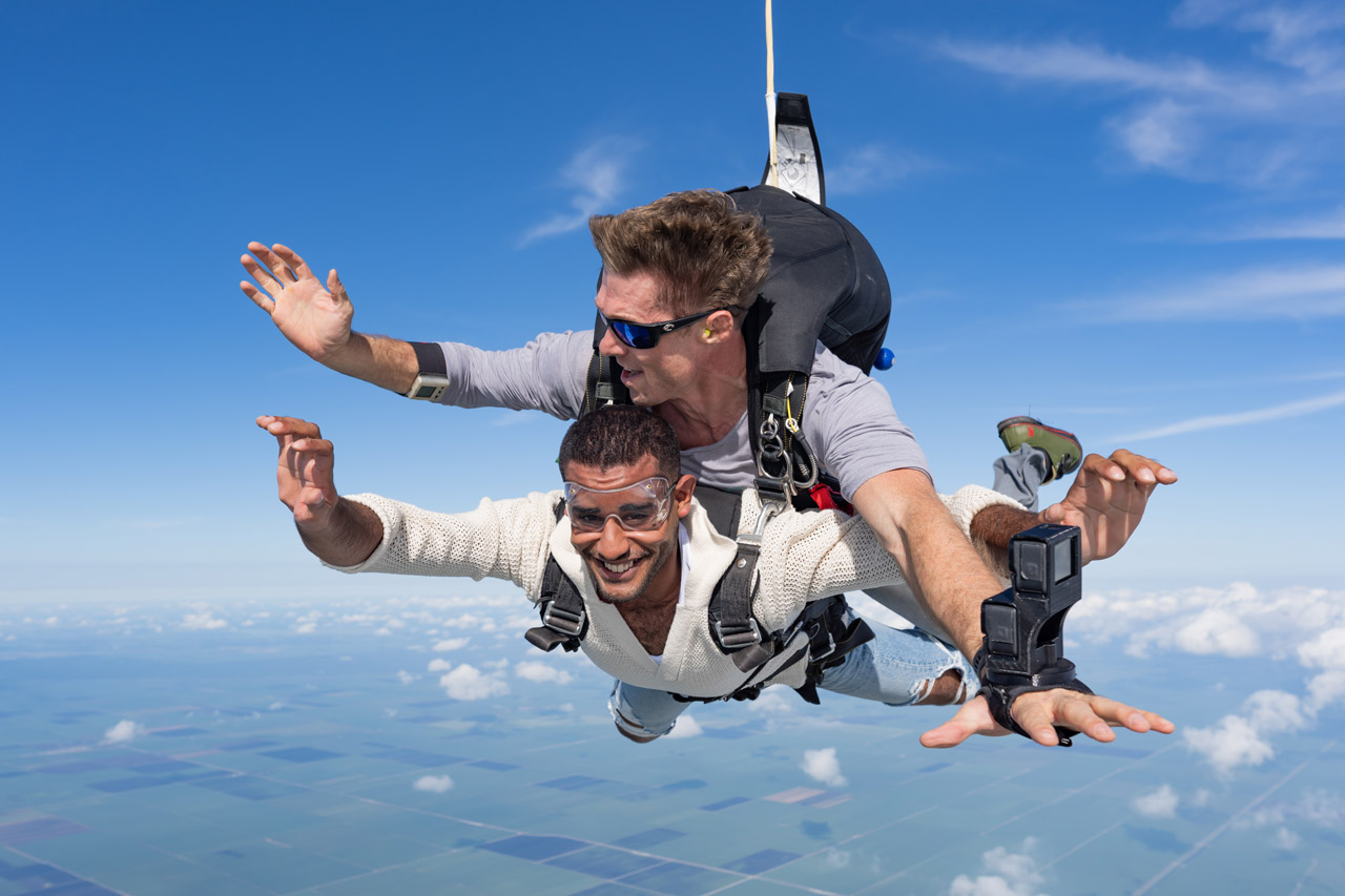 Male tandem skydiving student in white sweater in freefall above South Florida