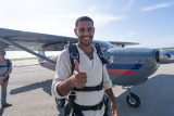 Male tandem skydiving student gives a thumbs up in front of an airplane at Skydive Palm Beach
