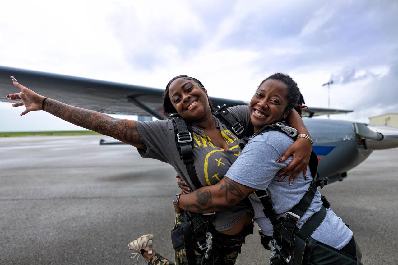 Two female tandem skydiving students hug and smile prior to their tandem skydive at Skydive Palm Beach