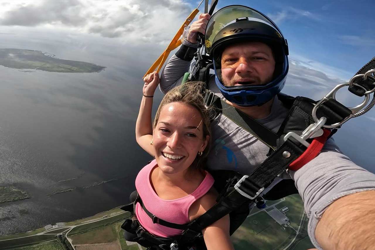 woman in pink shirt and tandem instructor steer the parachute
