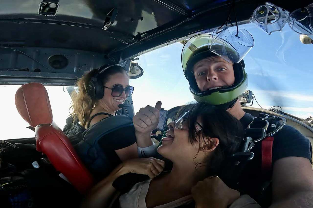 Tandem skydiving pair in the plane on the way to altitude. The female pilot and passenger are making eye contact.  