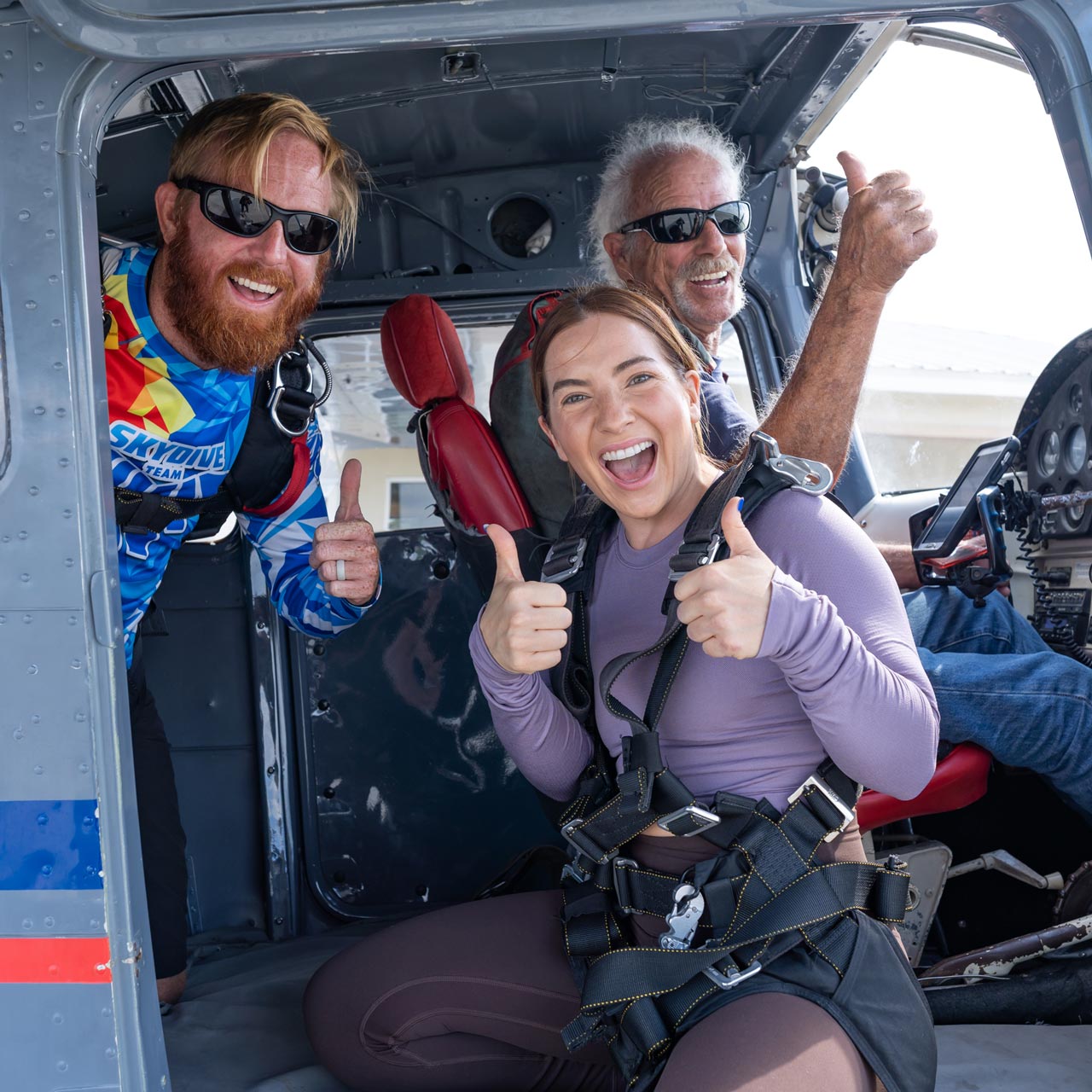 Tandem skydiving student, instructor, and pilot giving thumbs up in door of airplane at Skydive Palm Beach