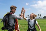 Tandem skydiving instructor high fives student after a tandem skydive