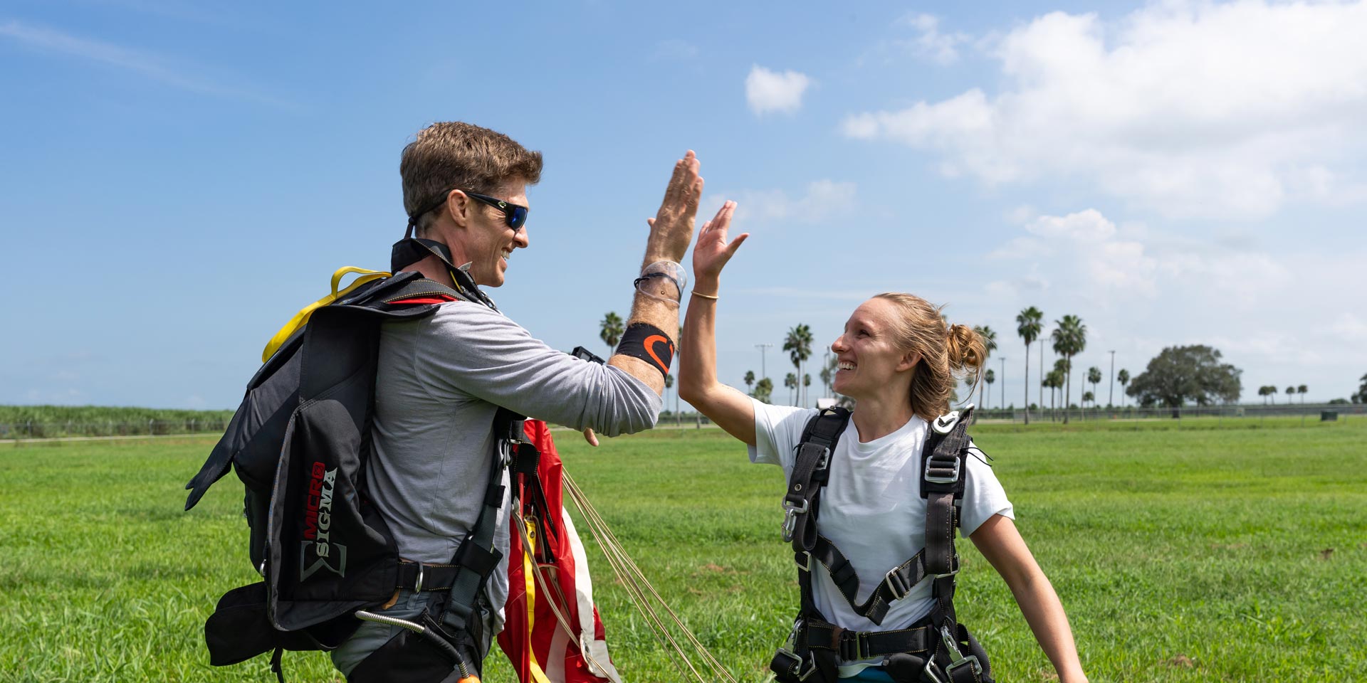 Tandem skydiving instructor high fives student after a tandem skydive