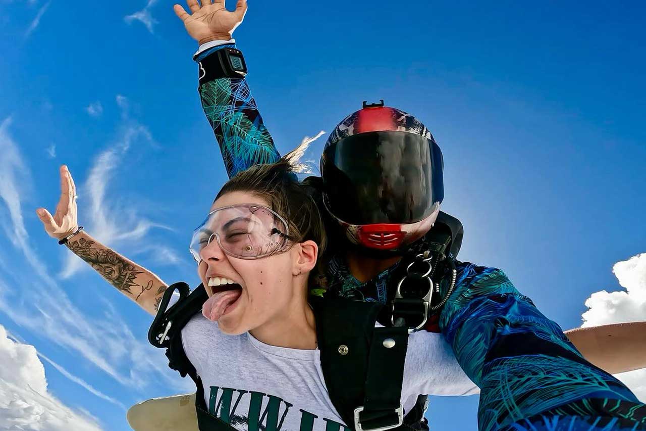 Female tandem skydiving passenger with clear goggles and open mouth