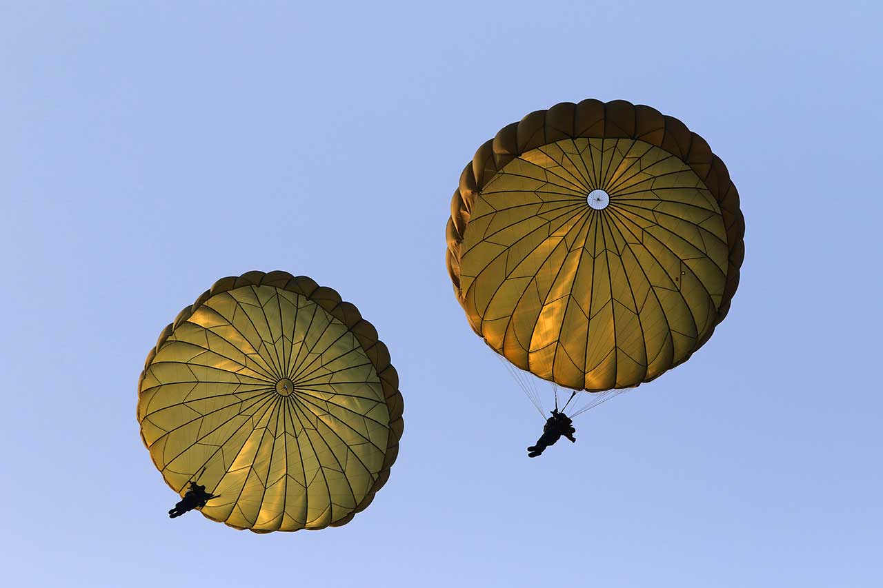 two military parachuters under round canopies