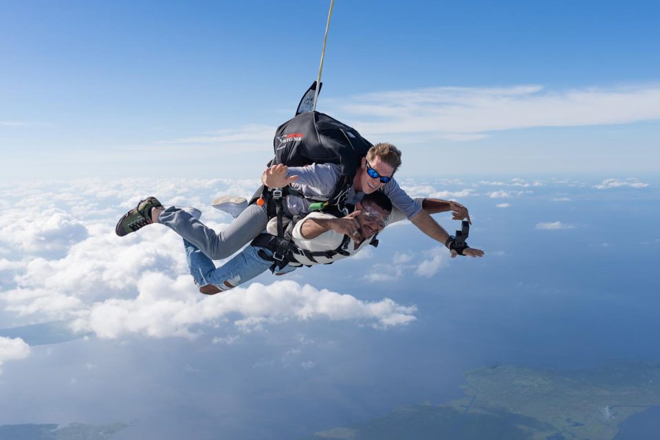 Male tandem skydiving student in white sweater in freefall above South Florida