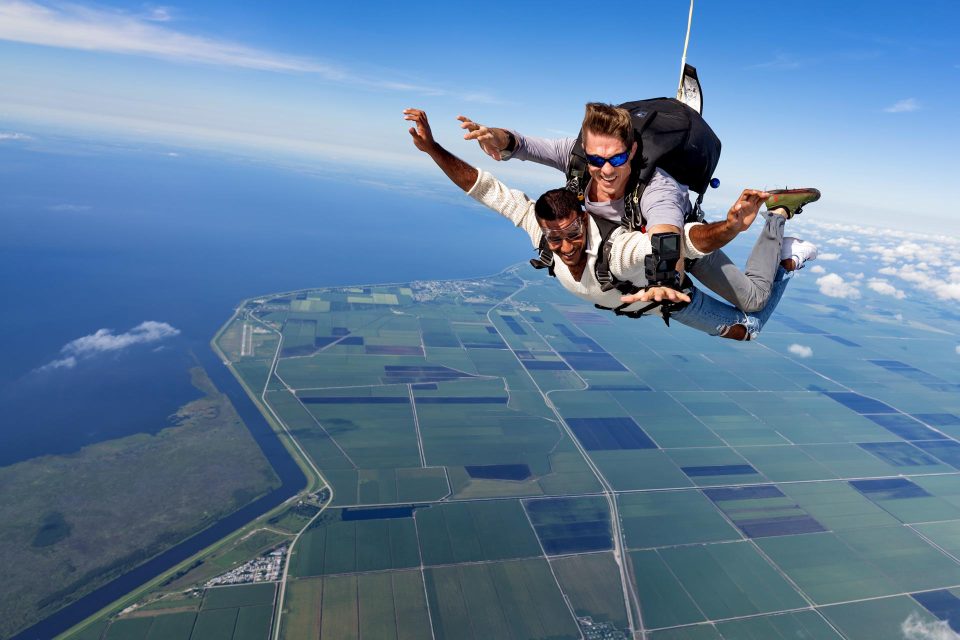 Male tandem skydiving student in white sweater in freefall above Lake Okeechobee in Florida