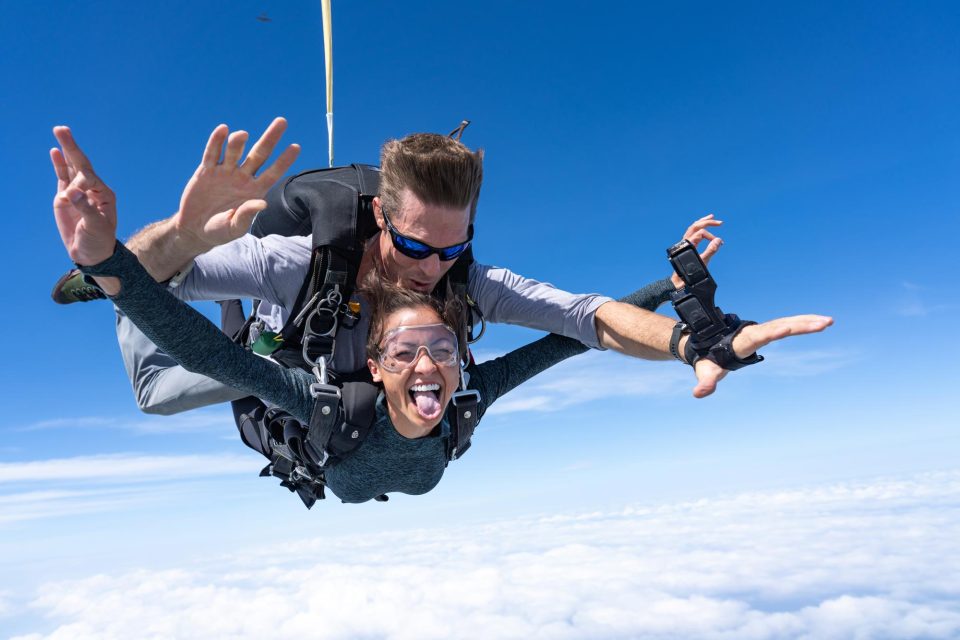 Tandem skydiving student sticks out tongue during freefall