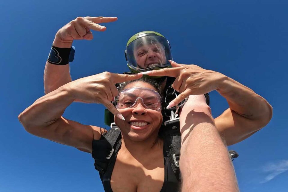 Tandem skydiver and her instructor displaying the rock on symbols