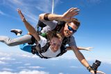 Female tandem skydiving student and male instructor in freefall with blue sky background