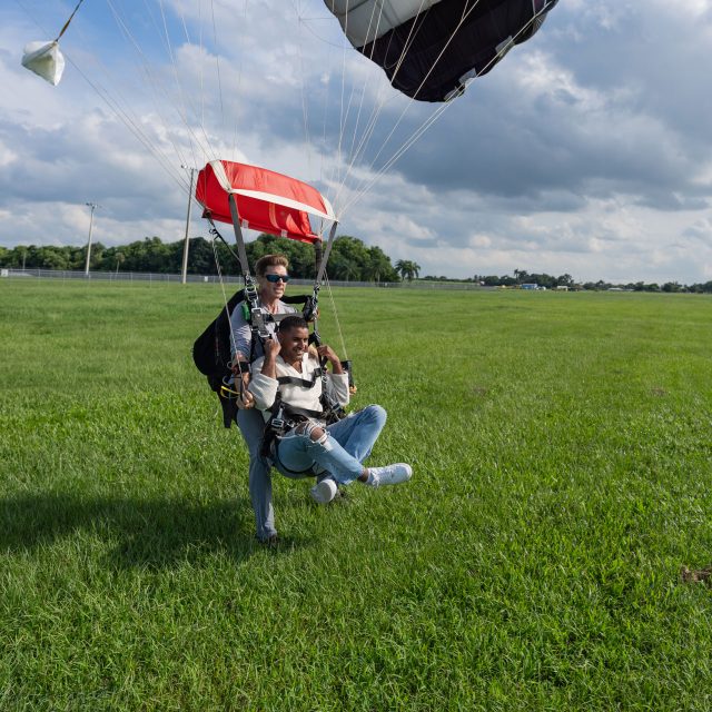 Tandem skydiving instructor and student land in a grassy field