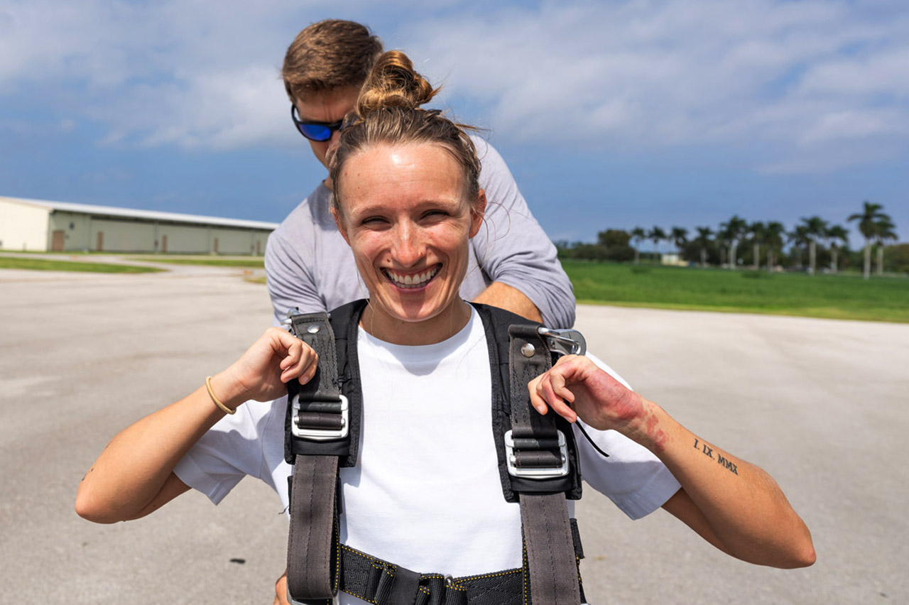 Tandem instructor helps tandem skydiving student gear up prior to a skydive near Fort Lauderdale
