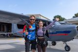 Tandem skydiving instructor and student smile for a photo in front of a skydiving plane at Skydive Palm Beach