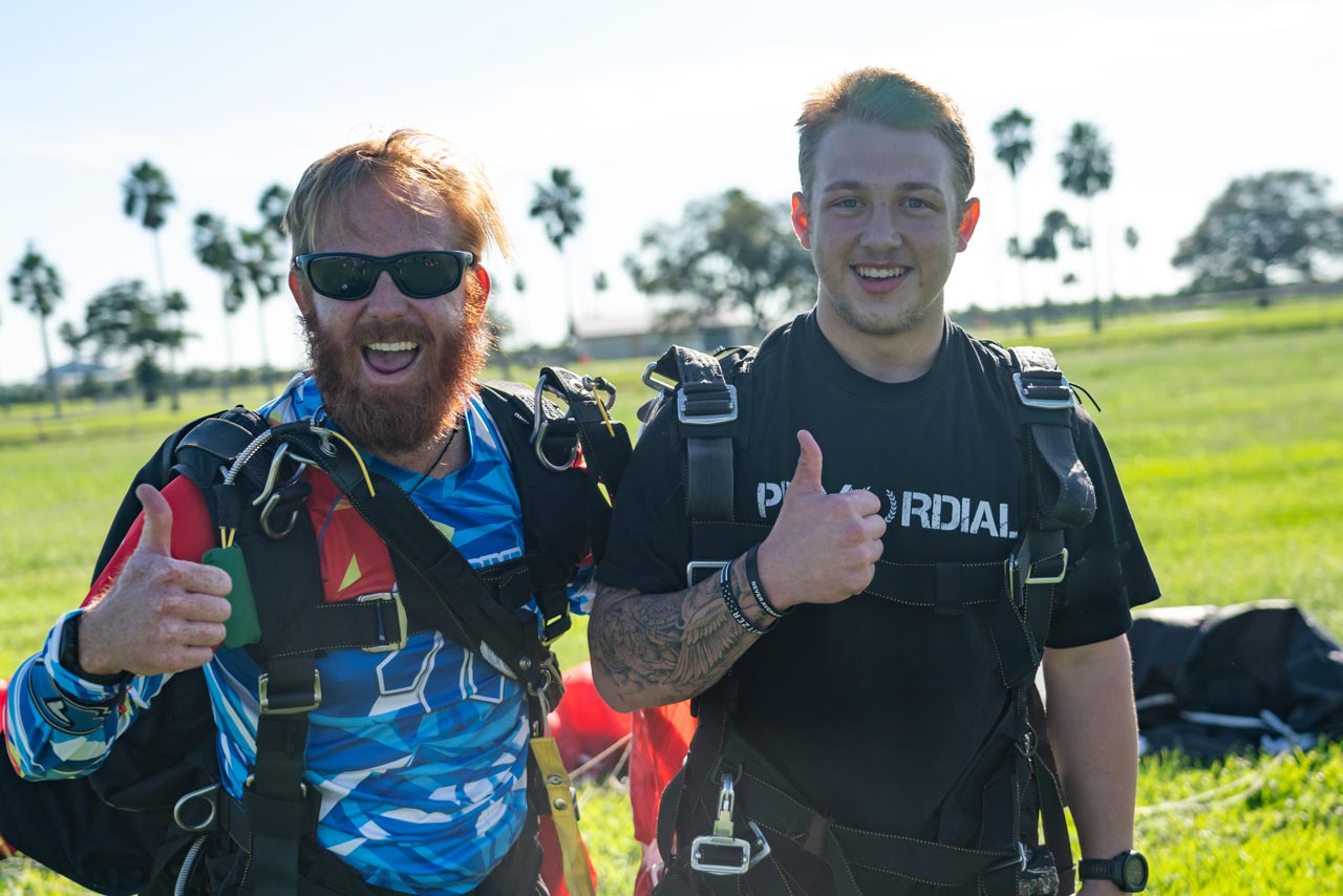 Tandem skydiving instructor and student give a thumbs up and smile after landing from a jump at Skydive Palm Beach